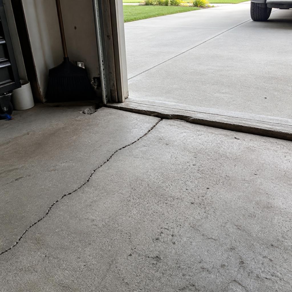 A garage floor with visible settlement along the slab edge